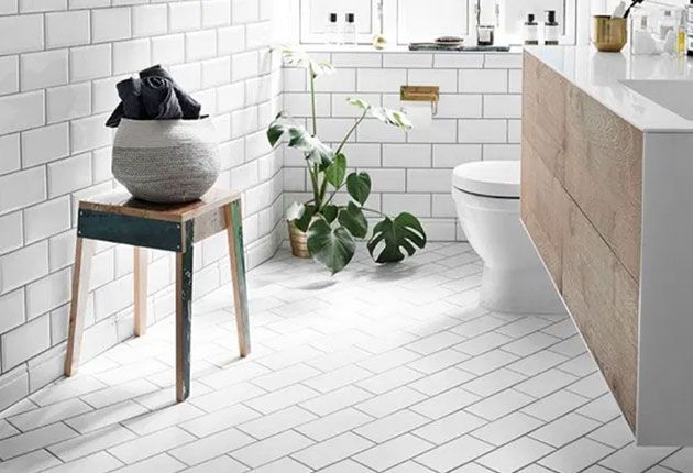 A bright Scandinavian-style bathroom with white subway tiles, a floating wooden vanity, and a modern toilet.