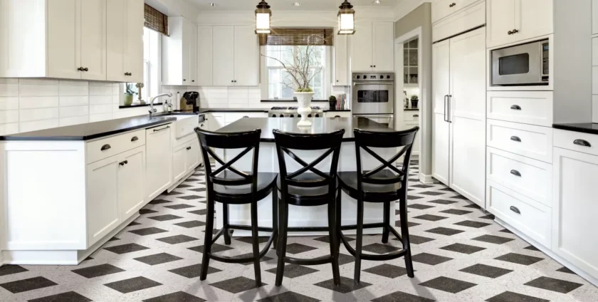 Elegant white kitchen with black countertops, patterned flooring, and a central island with black chairs.