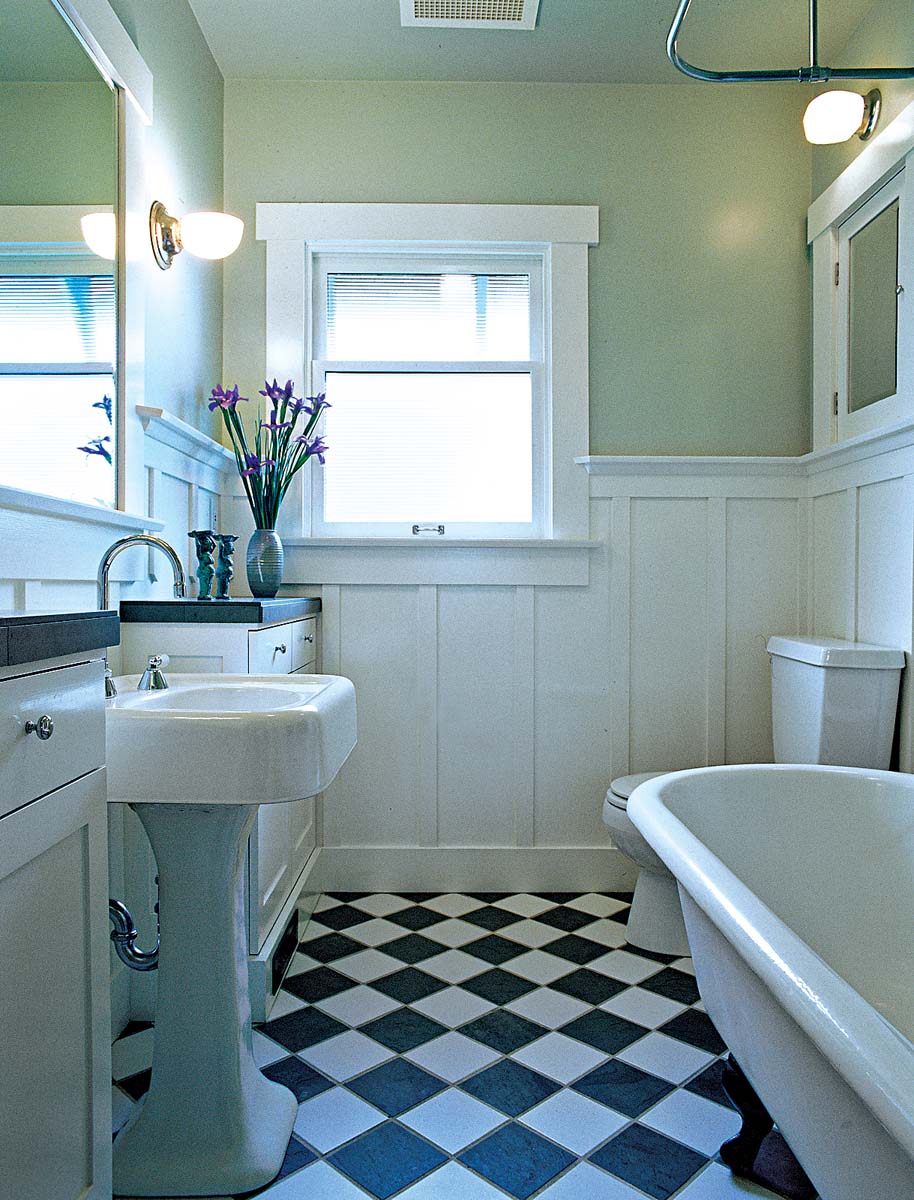 A charming vintage bathroom featuring a clawfoot bathtub, pedestal sink, and black-and-white checkered flooring