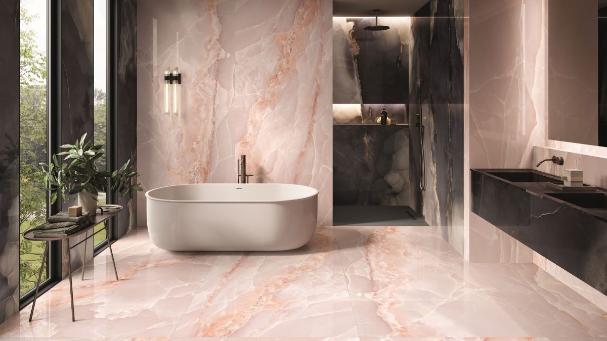 Elegant bathroom featuring a freestanding tub, black double vanity, and pink onyx tile walls and floor.