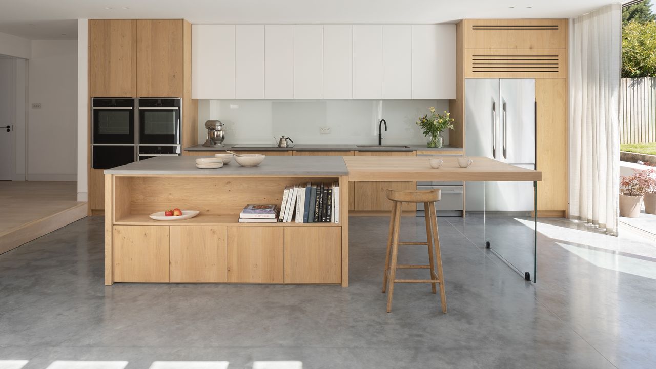 Minimalist modern kitchen with natural wood cabinets, white upper cabinetry, and concrete flooring