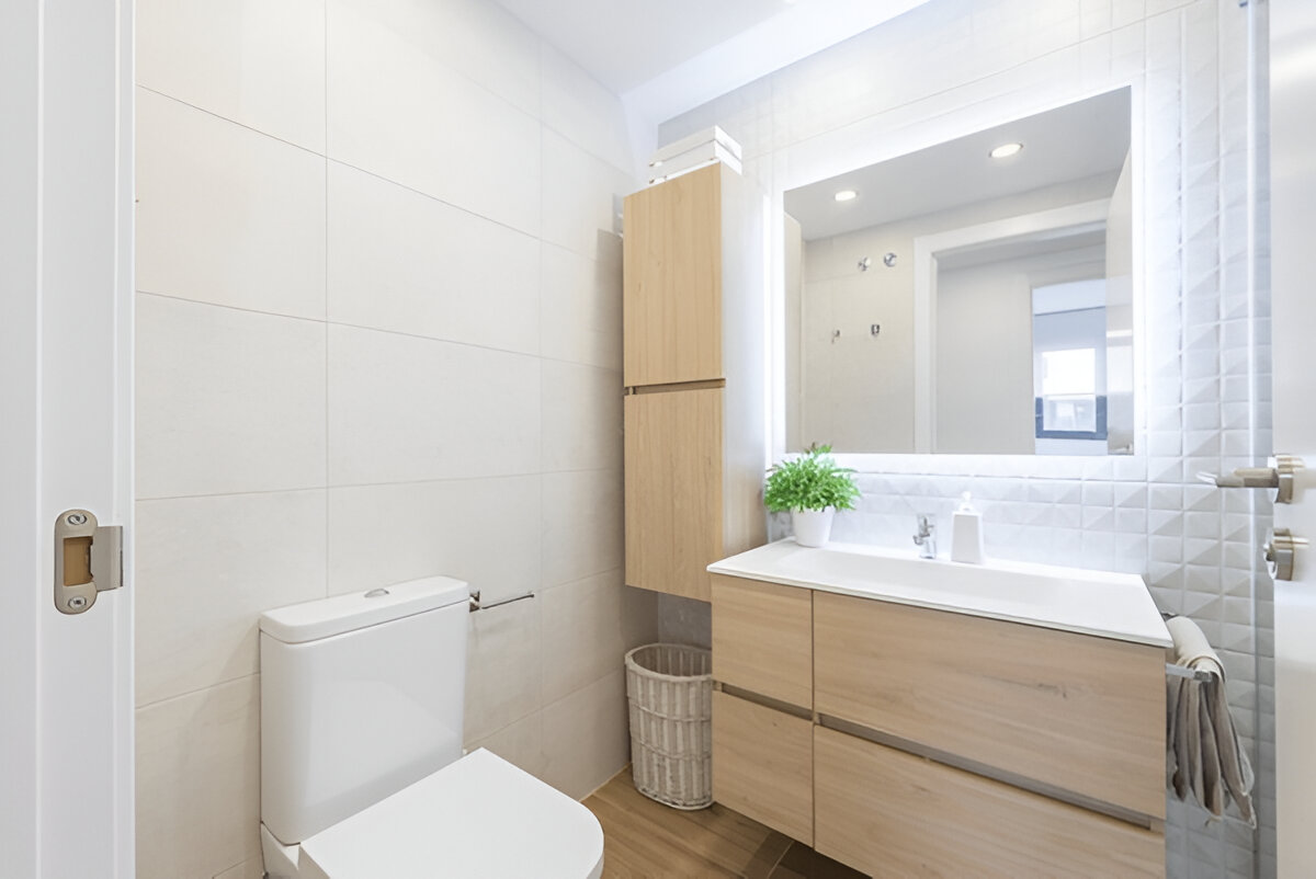 Minimalist bathroom with wood vanity, LED mirror, and white tiles