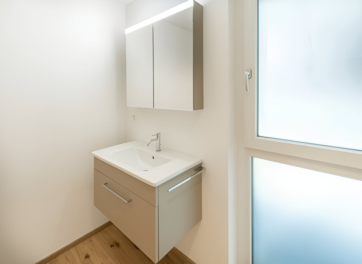 Modern white bathroom with floating vanity, mirror cabinet, and wood flooring