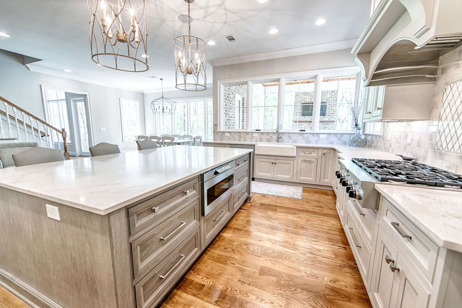Bright kitchen with quartz countertops, large island, farmhouse sink, and traditional cabinetry