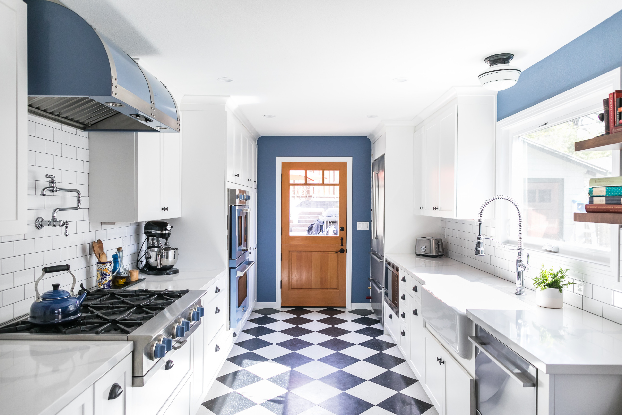 Bright galley kitchen with blue and white color scheme and checkered floor