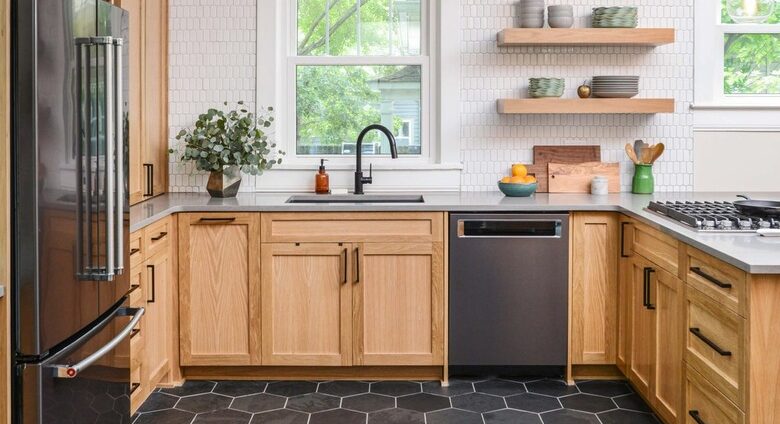 Modern kitchen with black hexagon tile flooring and natural wood cabinets.
