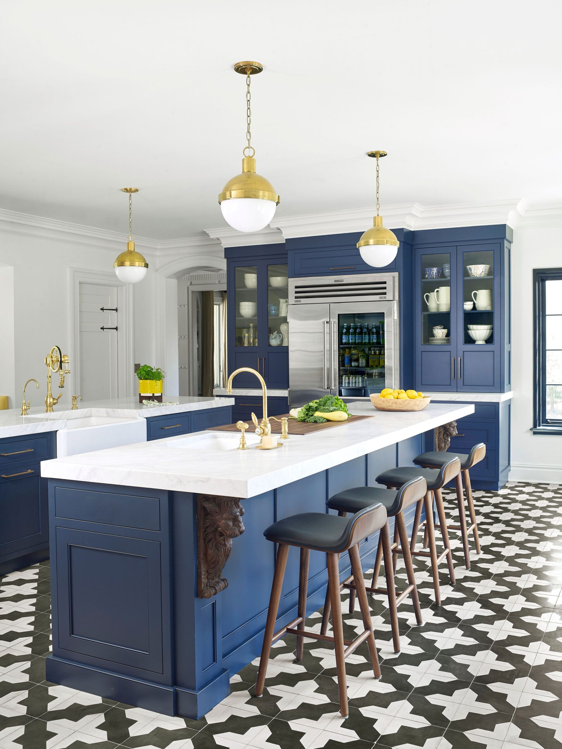 Elegant navy blue kitchen with gold fixtures and bold patterned tile flooring