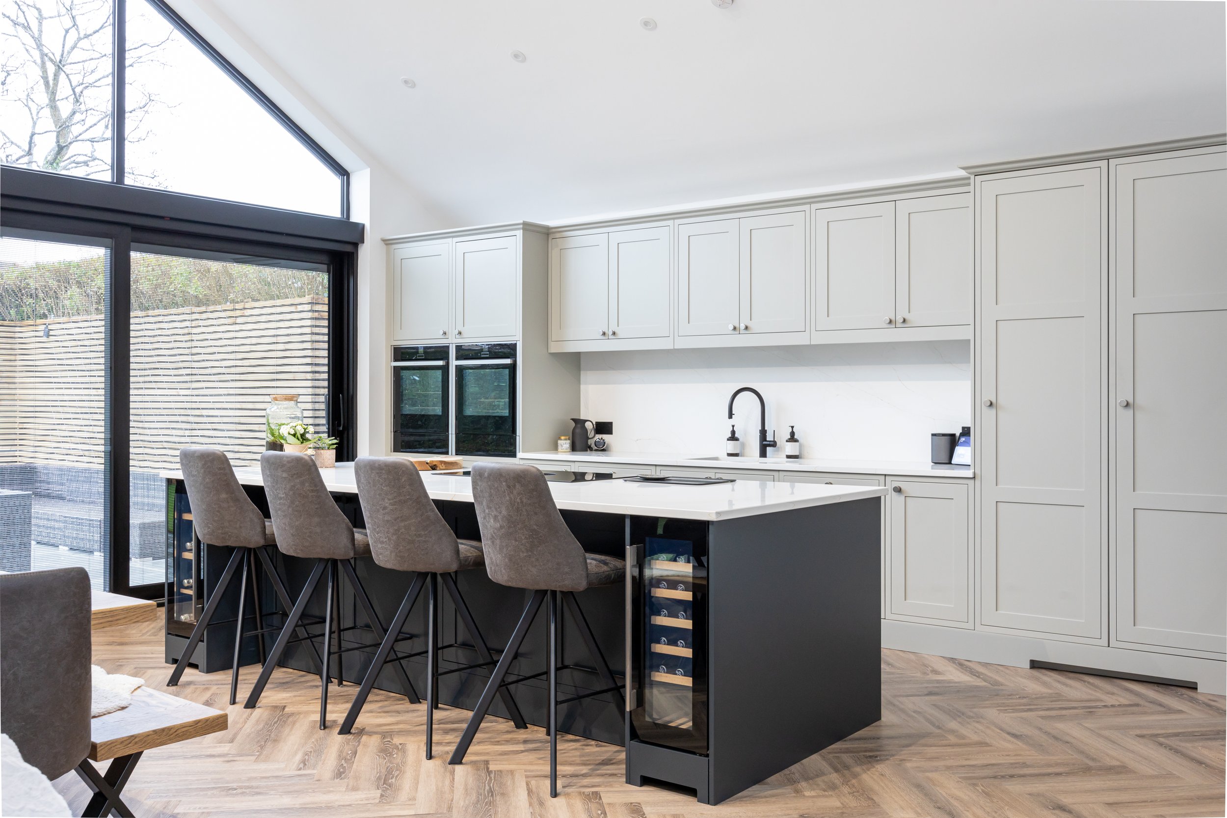 Modern minimalist kitchen with light gray cabinetry, black island, and bar seating