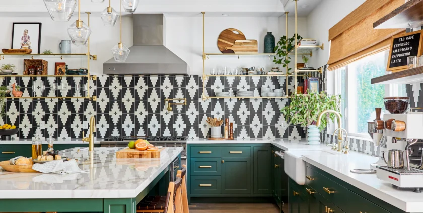 Bold black and white patterned kitchen backsplash with green cabinets and gold accents