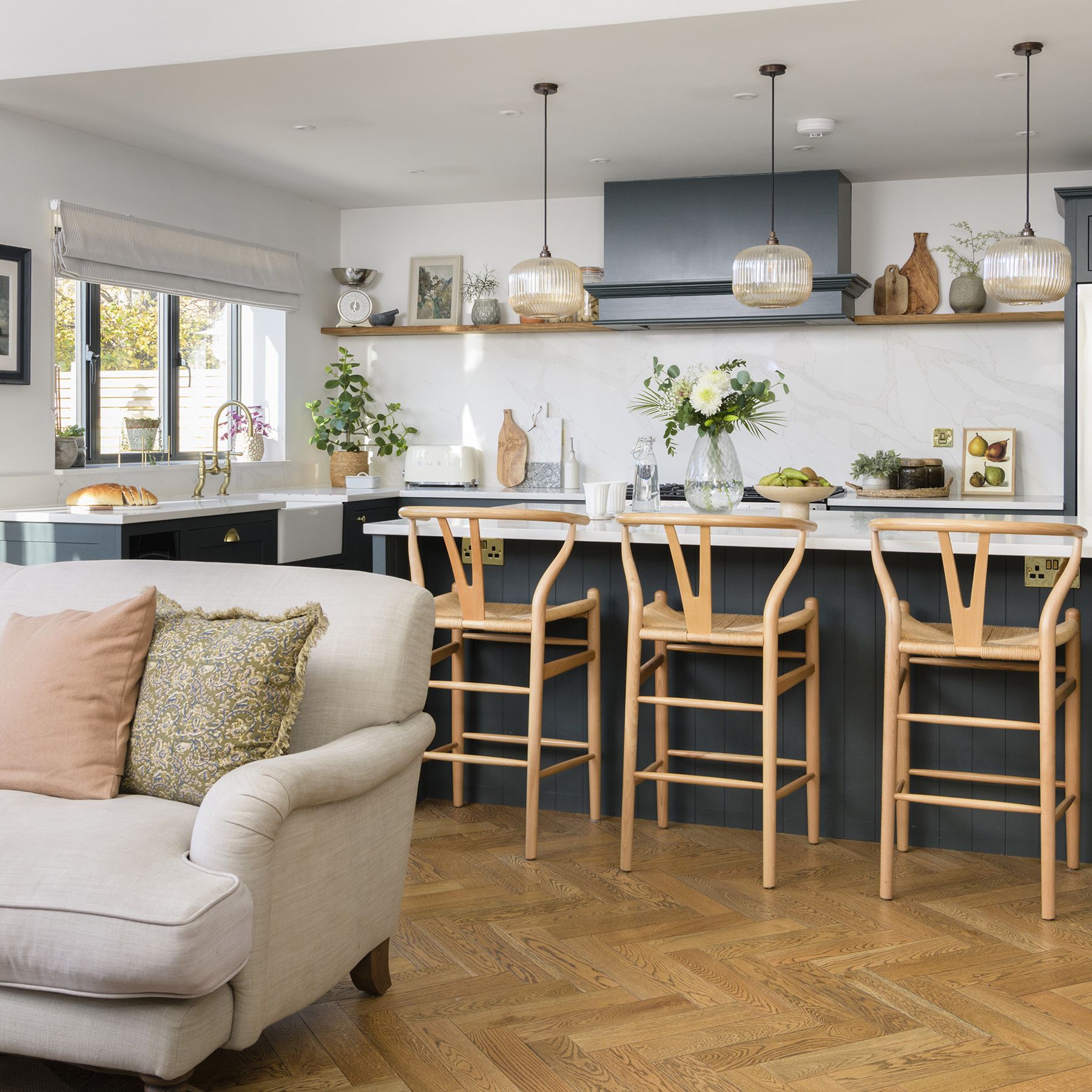 Cozy kitchen with herringbone wood flooring and light wood bar stools