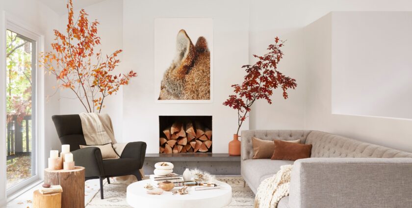 Minimalist living room with fall-inspired decor, cozy sofa, and stacked firewood.