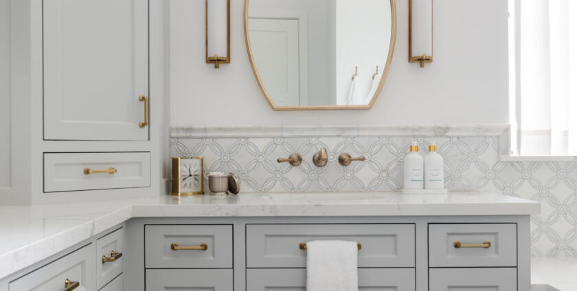 Elegant bathroom vanity with gray cabinets, gold hardware, and oval mirror