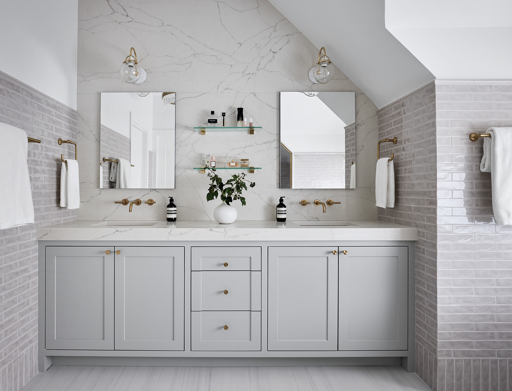 Modern gray double vanity bathroom with marble backsplash and gold fixtures