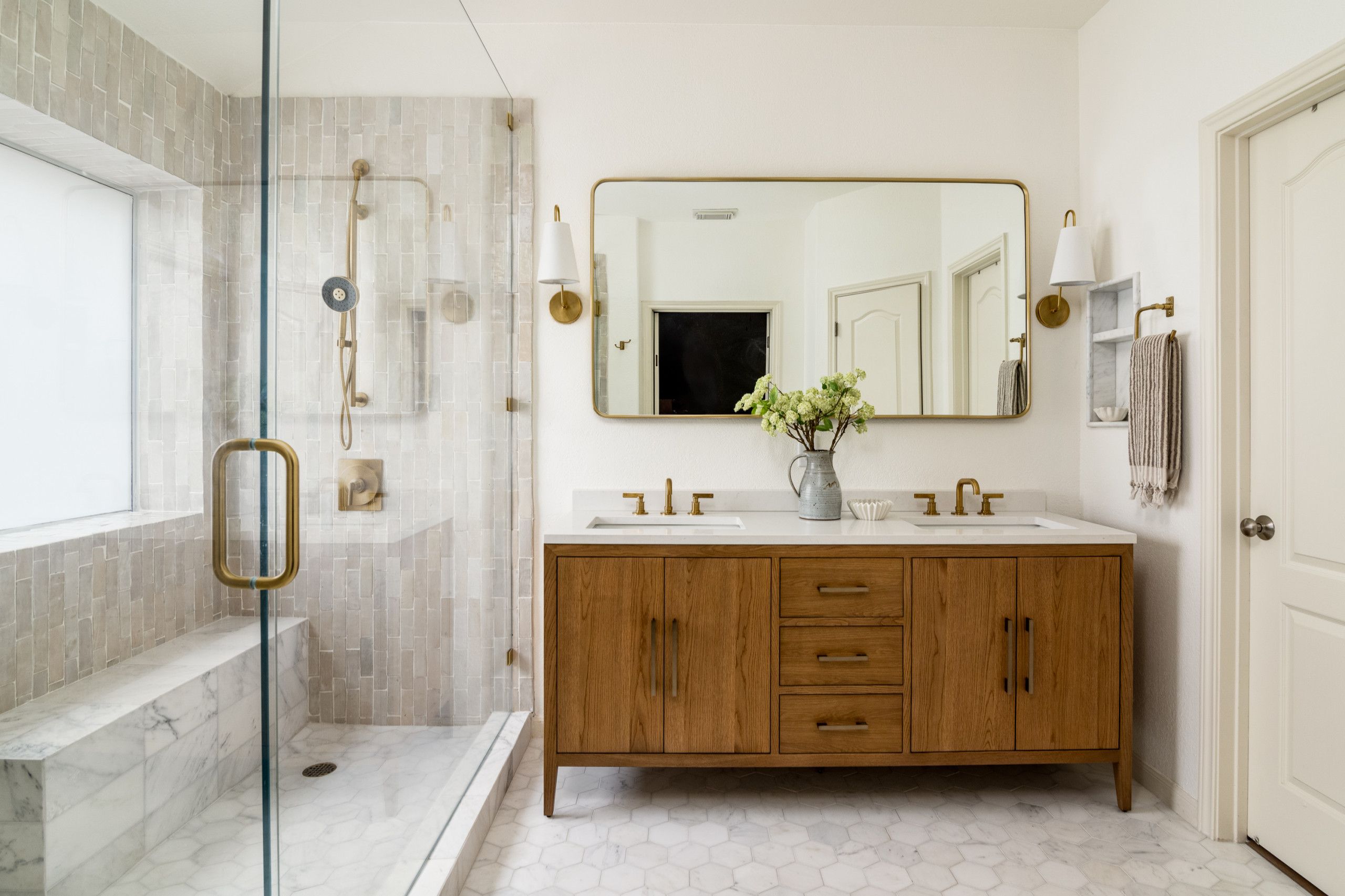 Modern bathroom with wood vanity, glass shower, and brass fixtures