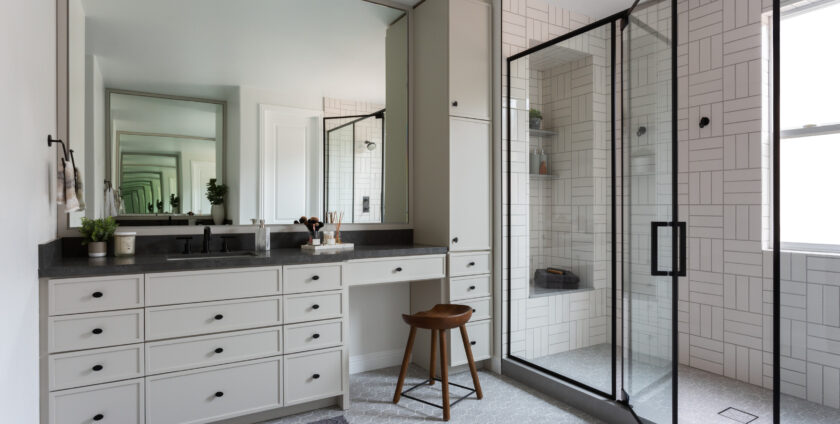Modern bathroom with large vanity, black-framed glass shower, and geometric tile design