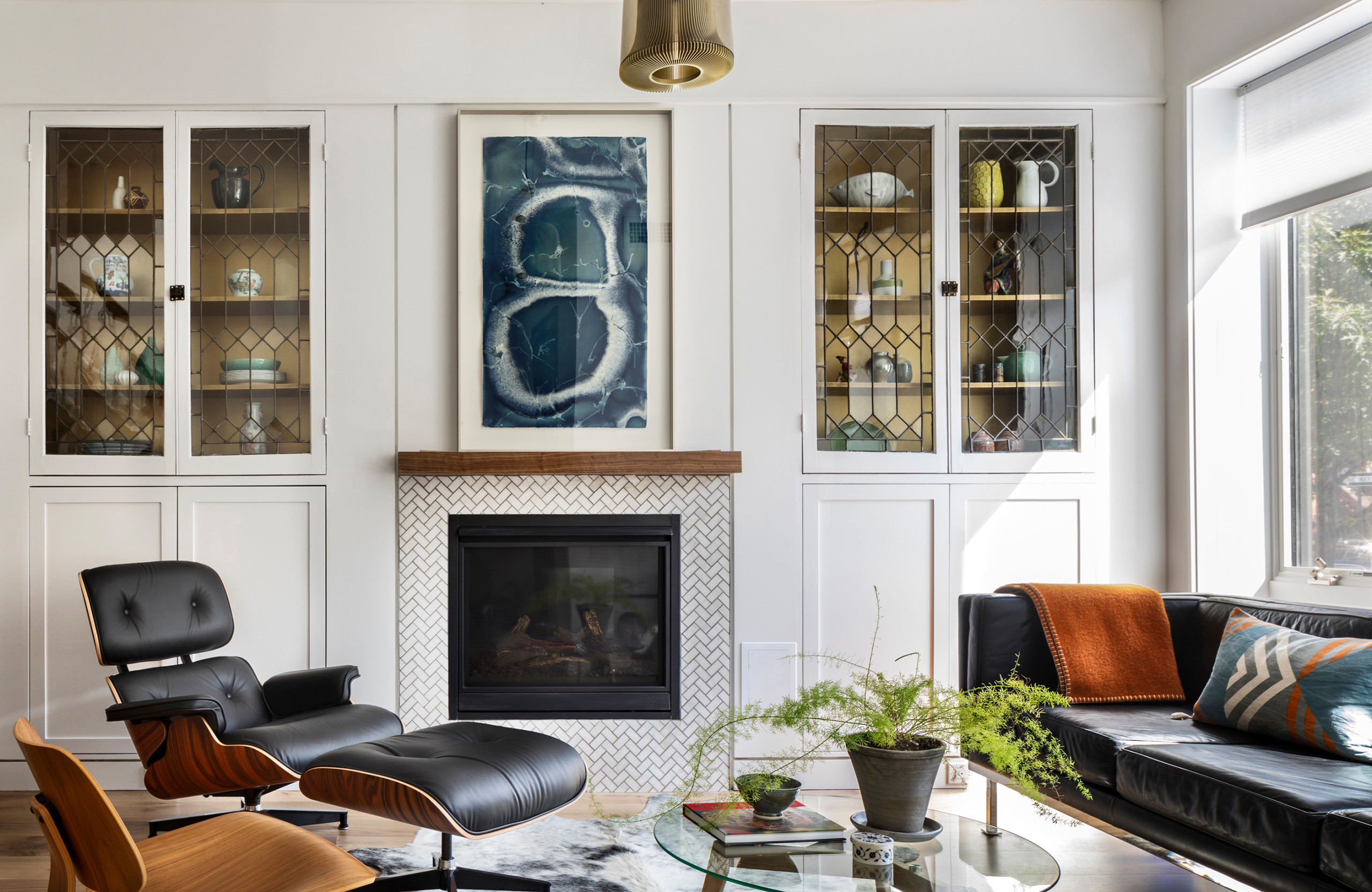 Mid-century modern living room with fireplace, black leather lounge chair, and glass coffee table