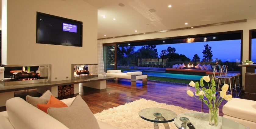 Modern open-concept living room with dual fireplace and poolside view