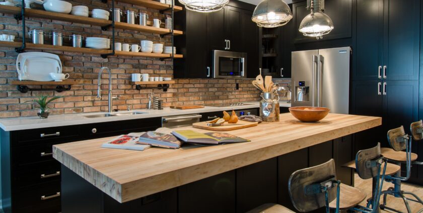 Industrial kitchen with exposed brick wall, open shelving, and wooden island