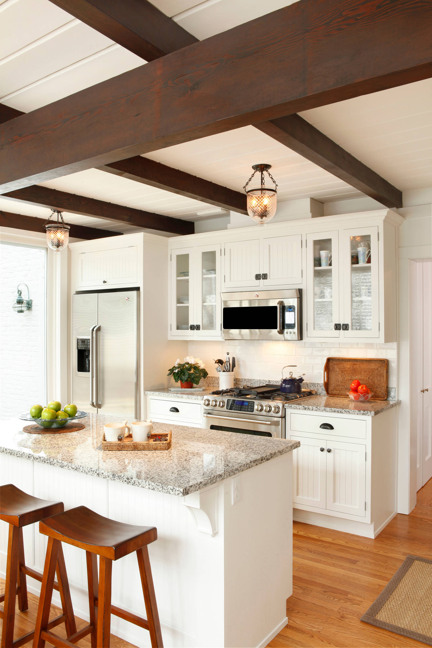 Cozy kitchen with white cabinets, granite countertops, and exposed wood beams