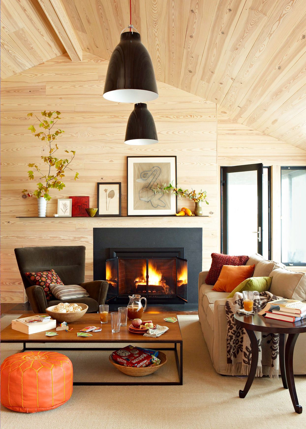 Cozy wood-paneled living room with fireplace, modern lighting, and colorful decor.