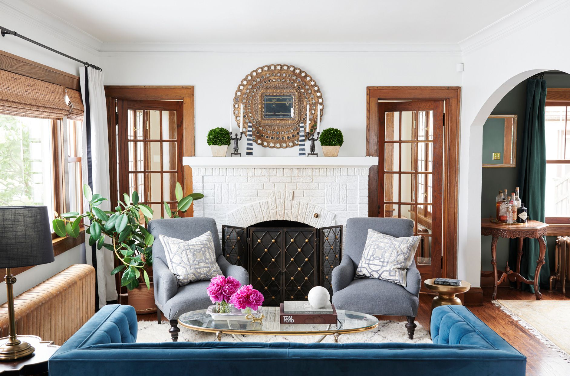 Living room with white brick fireplace, blue sofa, and gray armchairs.