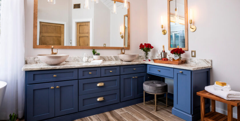 Elegant bathroom with navy blue cabinetry, marble countertop, gold fixtures, and wooden accents.